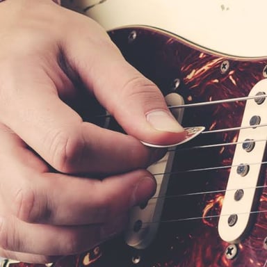 A guitarist using a pick to play a melodic lead part