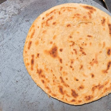 A bowl of atta flour beside round roti flatbreads.