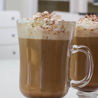A café mocha topped with foam in a coffeehouse setting.