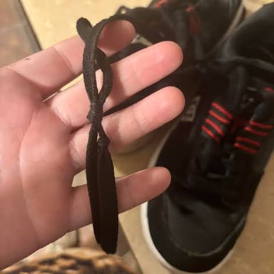 Hands loosening a knot in a pair of shoelaces.