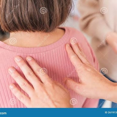 Hands applying pressure to a person's shoulder during a massage.