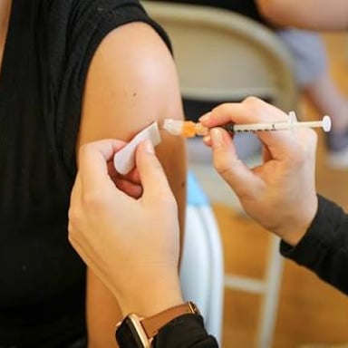 A healthcare worker administering an injection into a person's upper arm.