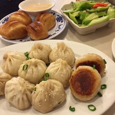 An assortment of dim sum, including dumplings and small buns, served in dishes and steamer baskets