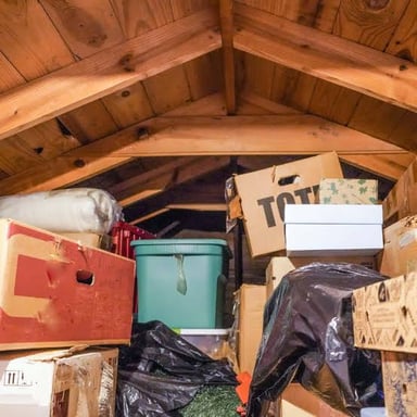 A small mouse near stored boxes in an attic.