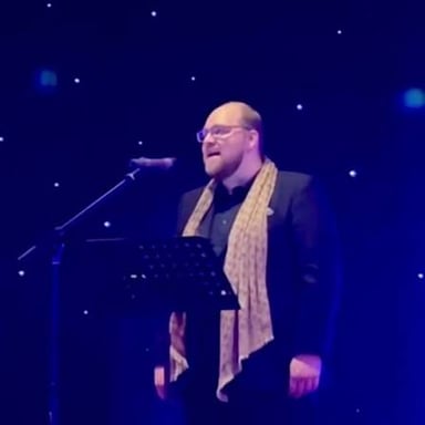 A tenor singer performing into a microphone.