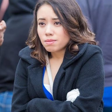 A person wrapped in warm clothing and visibly reacting to cold weather.
