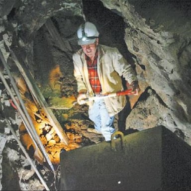 A miner holding a piece of mineral-bearing ore.