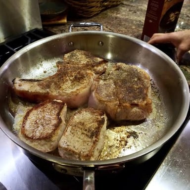 Browned cooking bits in a skillet being loosened with liquid to make a pan sauce.