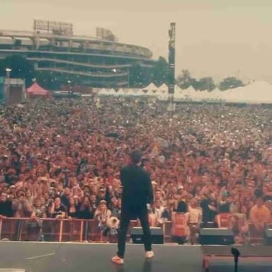 A crowd watching a band perform at a Vans Warped Tour outdoor concert.