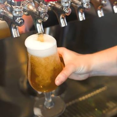 A pint of ale being poured from a tap.