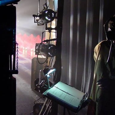 A stage manager backstage signaling an actor to make an entrance.