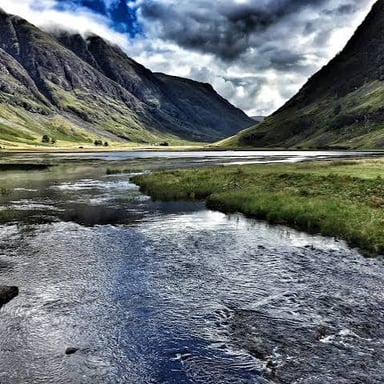 A green Scottish glen, a valley nestled among hills.